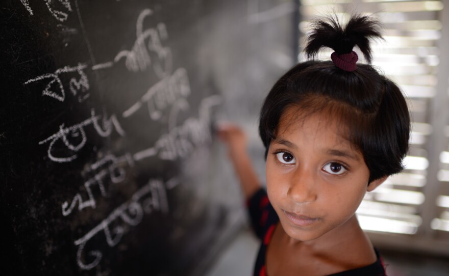 Rakhu Khatun, age 9, writes on the blackboard, which sits in front of the boat's engine.