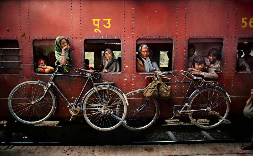 Bicycles hang on the side of a train traveling from Dacca to Peshawar, West Bengal, India. April 1993.