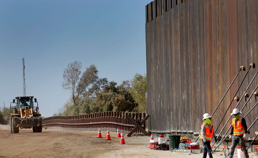 In this Sept. 10, 2019, file photo, government contractors erect a section of Pentagon-funded border wall along the Colorado River, in Yuma, Ariz.