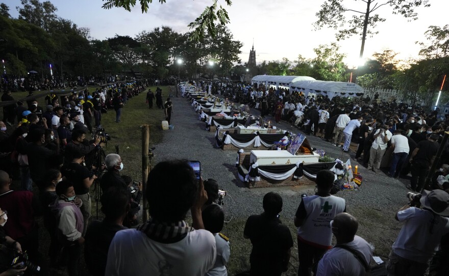 A long row of coffins containing victims in the day care center attack sit atop funeral pyres before cremation.