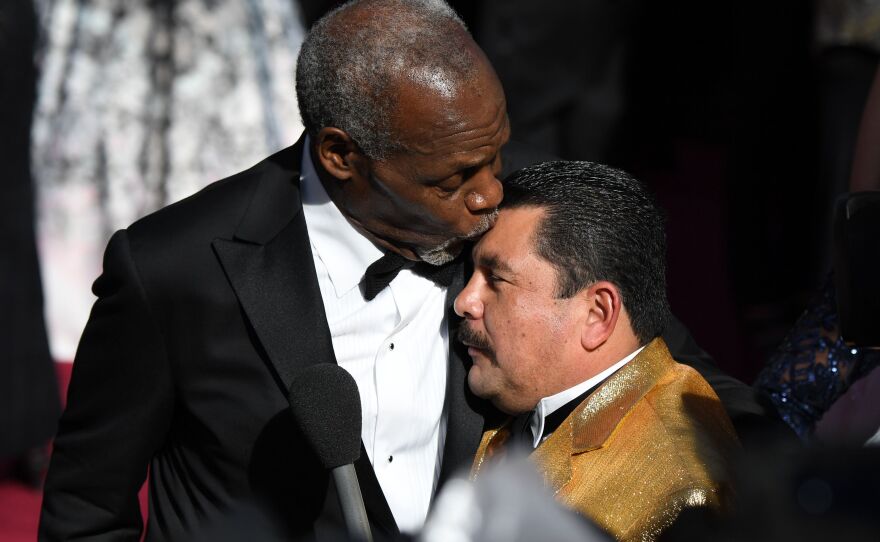 Actor Danny Glover kisses TV host Guillermo on the head.