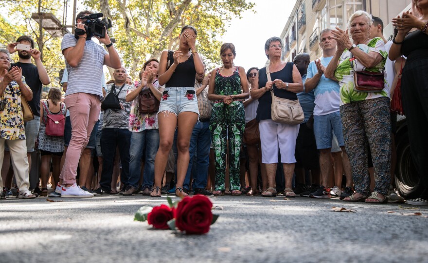 People gather around a single rose laid on the ground of Las Ramblas in Barcelona on Friday, observing one minute's silence for the victims of the terrorist attack.