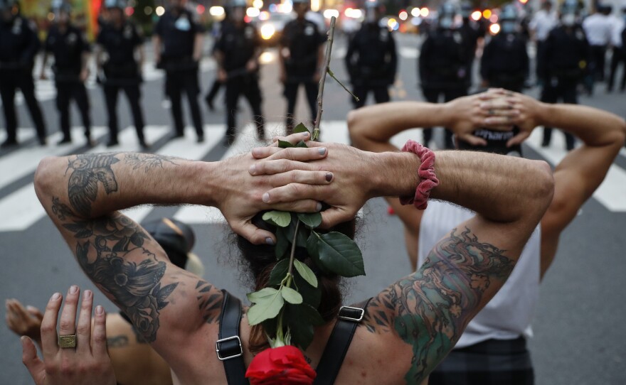 Protesters kneel in front of New York City police officers before being arrested for violating curfew on Wednesday.
