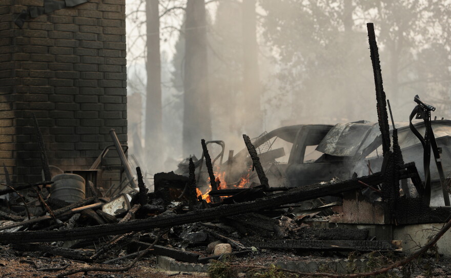 A home on N. Victor St. and W. Lyons Ave. burned by a wildfire smolders on Aug. 2, 2026, in Spokane, Wash.