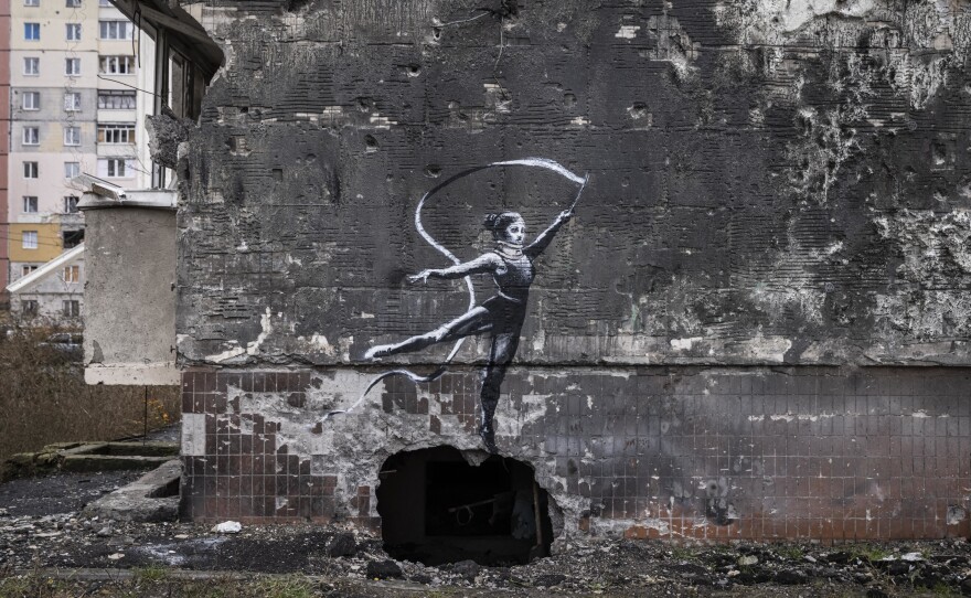 Graffiti of a woman in a leotard and a neck brace waving a ribbon is seen on the wall of a destroyed building in Irpin on Friday.