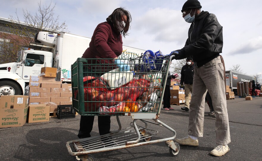 A volunteer loads food into a cart at a mobile pantry in Detroit in April 2020. The COVID-19 pandemic has led to an uptick in the demand at food banks.