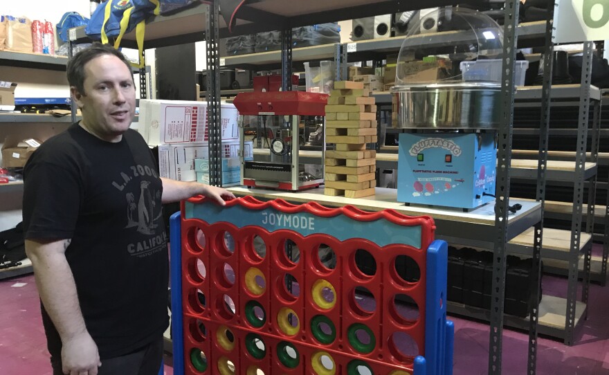 Joe Fernandez stands next to a giant Connect Four set in his company’s downtown Los Angeles warehouse, Feb. 5, 2018.