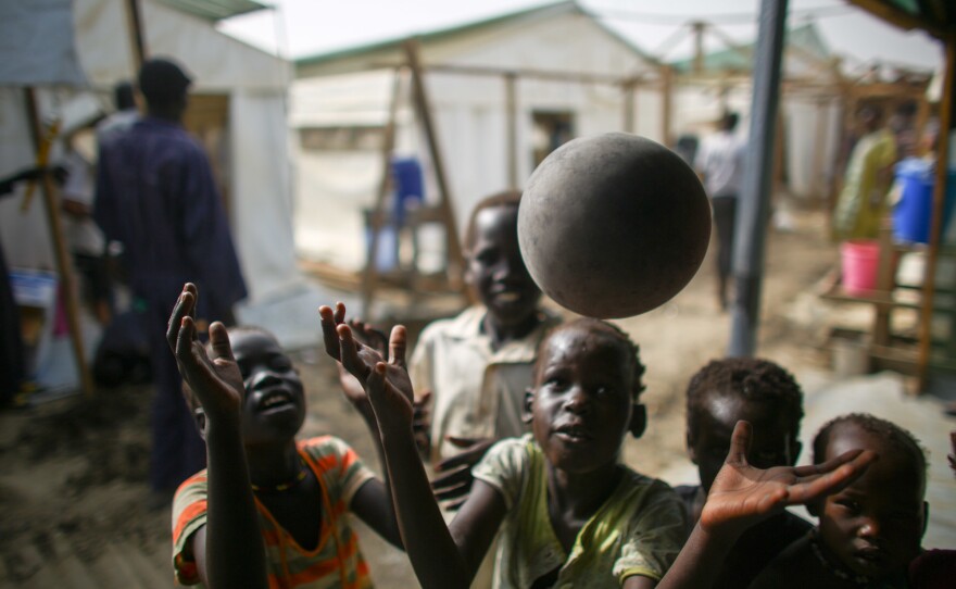 Kids who are waiting inside the hospital compound play with a balloon outside the wards.