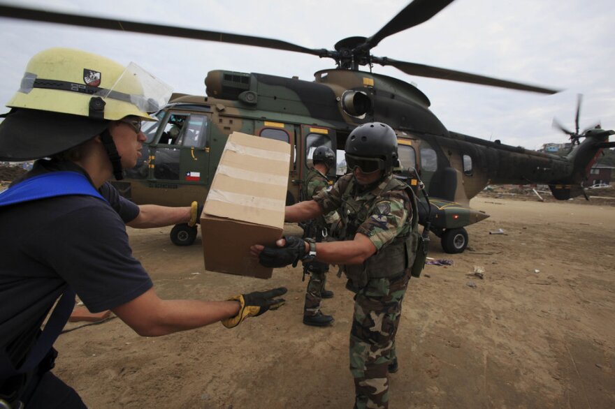 Chilean troops and firefighters unload relief supplies Wednesday from a military helicopter in the coastal town of Dichato, which was heavily damaged by tsunami waves produced by Saturday's 8.8-magnitude earthquake.