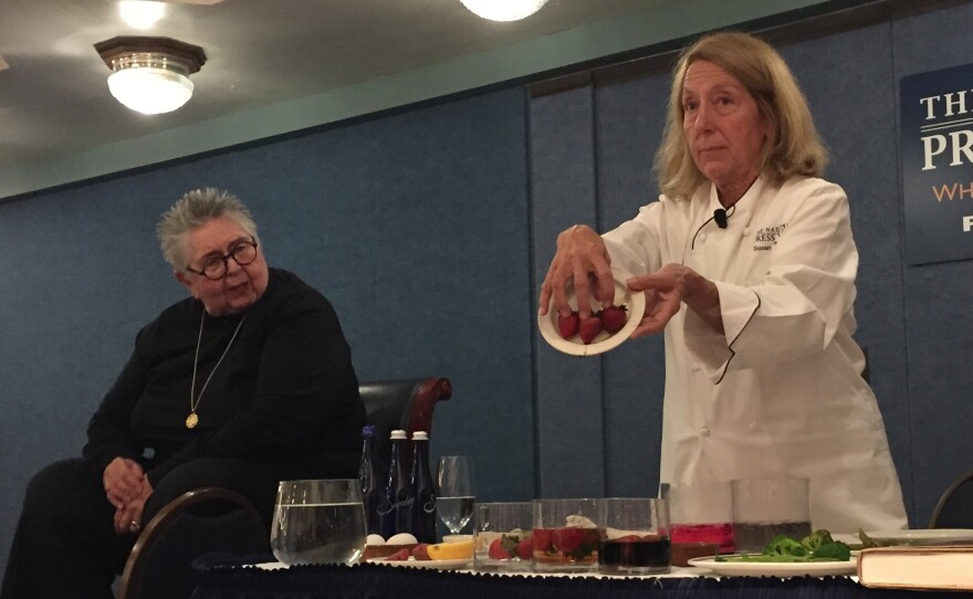 The National Press Club's Executive Chef Susan Delbert shows off how strawberries change color while Shirley Corriher (left) explains strawberries are very absorbent and will pick up the color of the solution they're placed in.