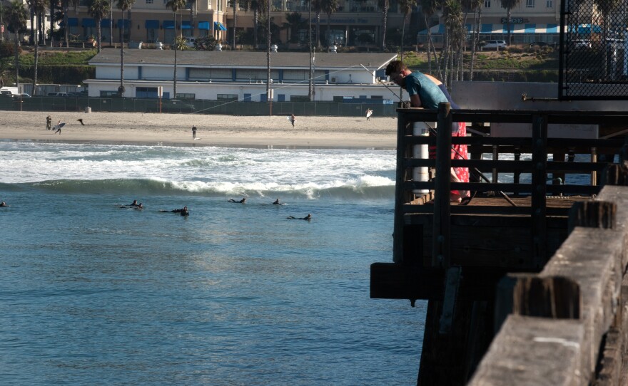 A Fisherman looks over the railing on the public side of the Oceanside Pier on Oct. 23, 2024.