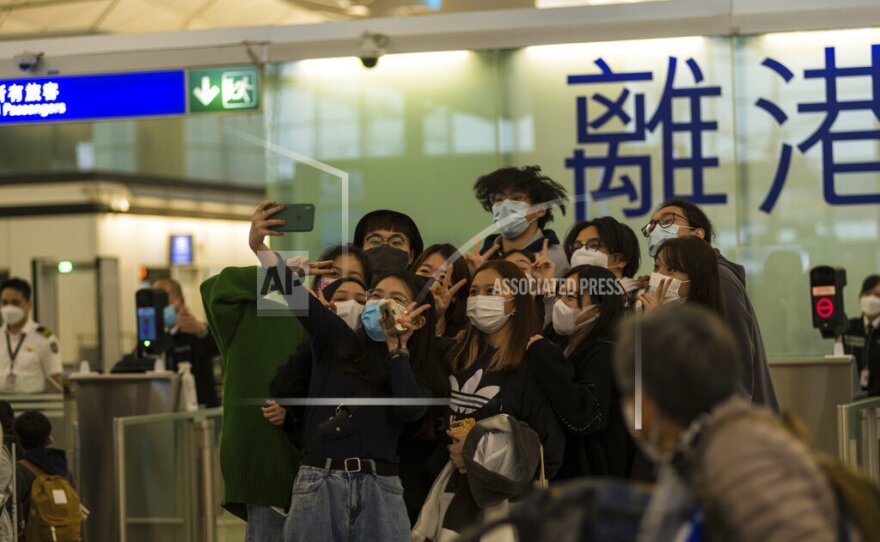 Travelers and friends pose for a selfie before entering the immigration area of the departure hall in the Hong Kong International Airport on April 2, 2022.