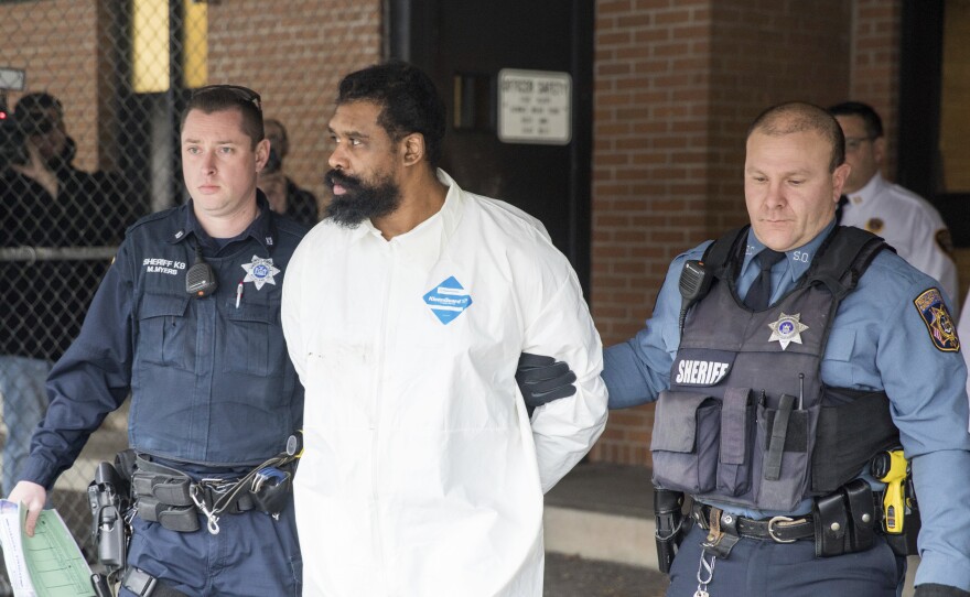 Ramapo police officers escort Grafton Thomas from Ramapo Town Hall to a police vehicle on Sunday. Thomas is accused of stabbing multiple people as they gathered to celebrate Hanukkah at a rabbi's home in the Orthodox Jewish community north of New York.