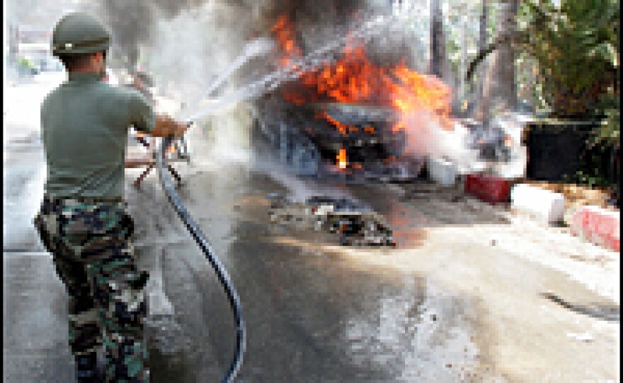 A Lebanese soldier tries to extinguish a car that was bombed in front of a hospital by an Israeli warplane July 23, 2006.