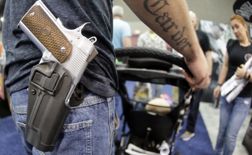 Donald Carder wears his handgun in a holster as he pushes his son, Waylon, in a stroller at the National Rifle Association convention in May in Louisville, Ky. Attendees at the convention are permitted to carry firearms under Kentucky's open-carry law.