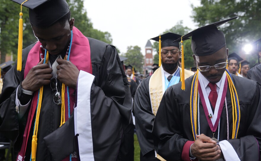 Graduating students at the Morehouse College commencement bow their heads Sunday in Atlanta. President Biden addressed the graduating class of 2024 and warned about "extremist forces" he says threaten the soul of the nation.