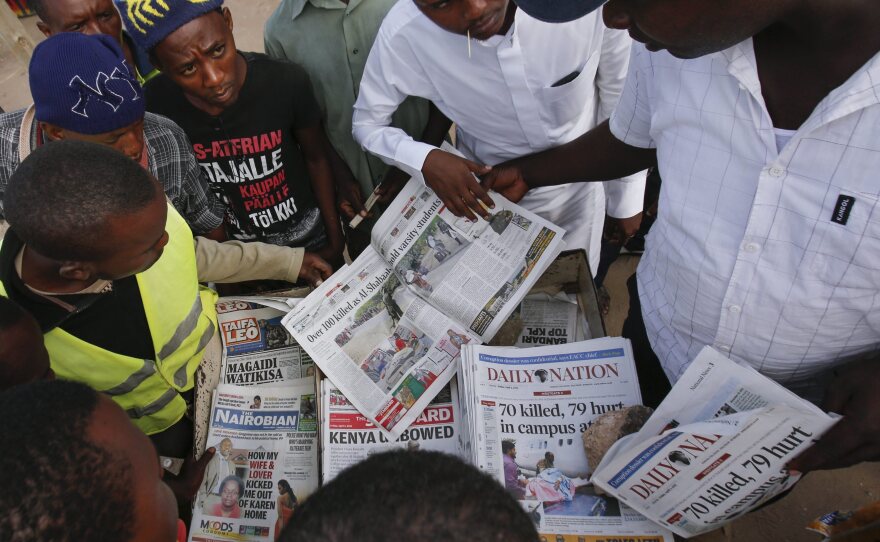 Local residents gather around a newspaper vendor to read articles on an attack on Garissa University College in Garissa town Friday.