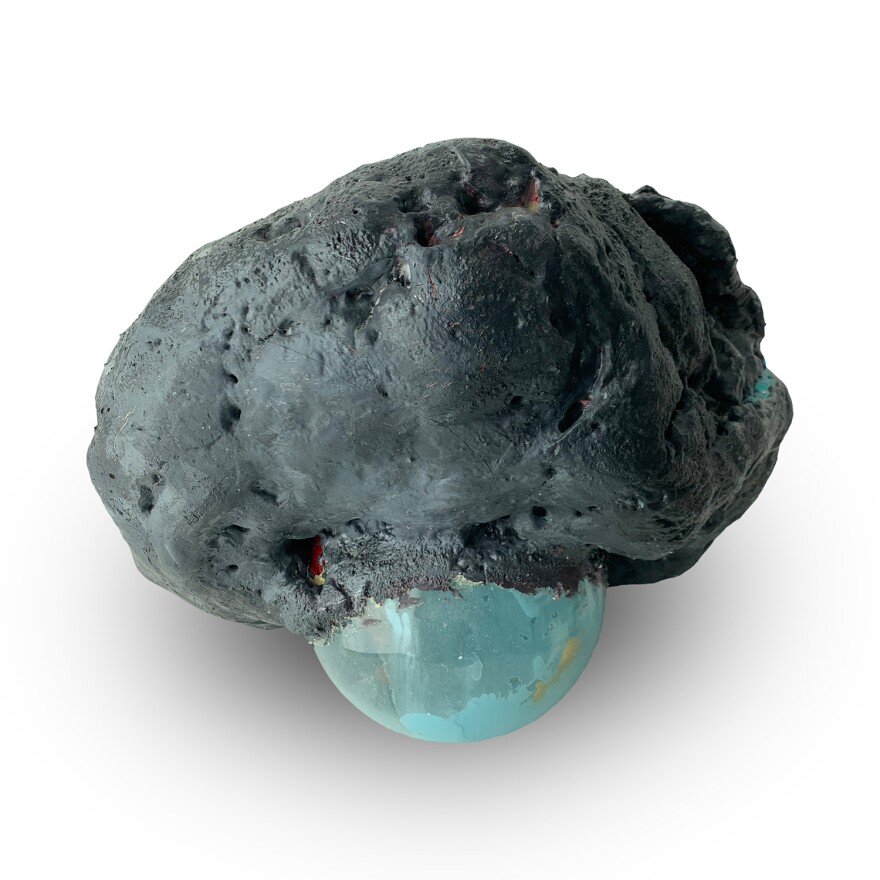 A sculpture appears to show a small, glass blue orb emerging from a gray rock.