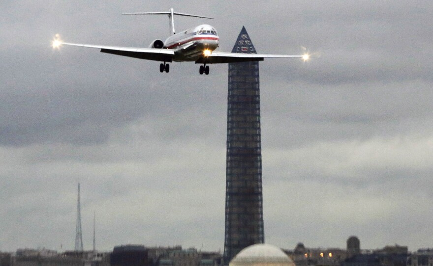 An American Airlines jet passes the Washington Monument as it lands at Ronald Reagan National Airport. That's one of seven airports where American and US Airways must now make room for low-cost competitors under a settlement with the Justice Department.