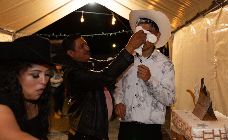 A family member cleans Kevin's face after the <em>mordida</em>, a Mexican tradition when the birthday boy or girl's face is shoved into a cake for them to take the first bite as they're surrounded by their loved ones chanting <em>Mor-di-da! Mor-di-da!</em>