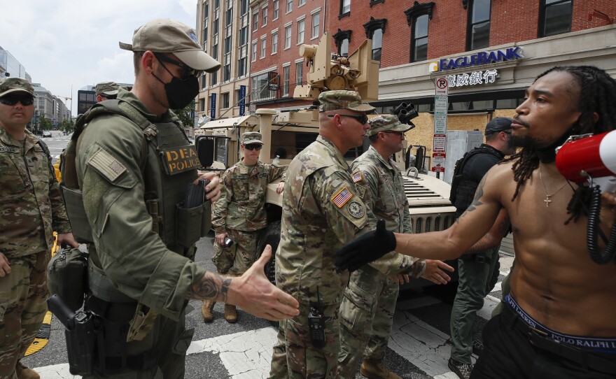 Demonstrator Aaron Covington shakes hands with National Guard troops and DEA police at a protest in Washington on Saturday over the death of George Floyd. President Trump announced that the National Guard forces would be pulling out of the nation's capital after several days of peaceful demonstrations.