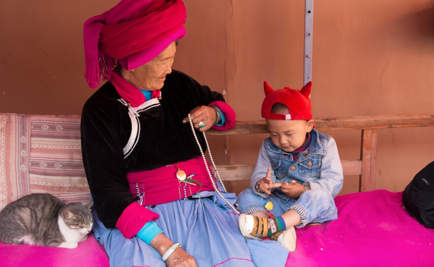 Zhaba Songding's grandmother, Ani Ciru, 77, sits with Zhaba's son Luosang Nyima, 2, and cat in their courtyard.