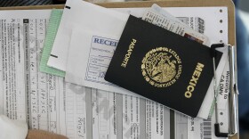 Miguel Ayala holds his application with his Mexican passport while waiting in line with other immigrants at a California Department of Motor Vehicles office to register for drivers licenses in Stanton, Calif., Jan. 2, 2015. 