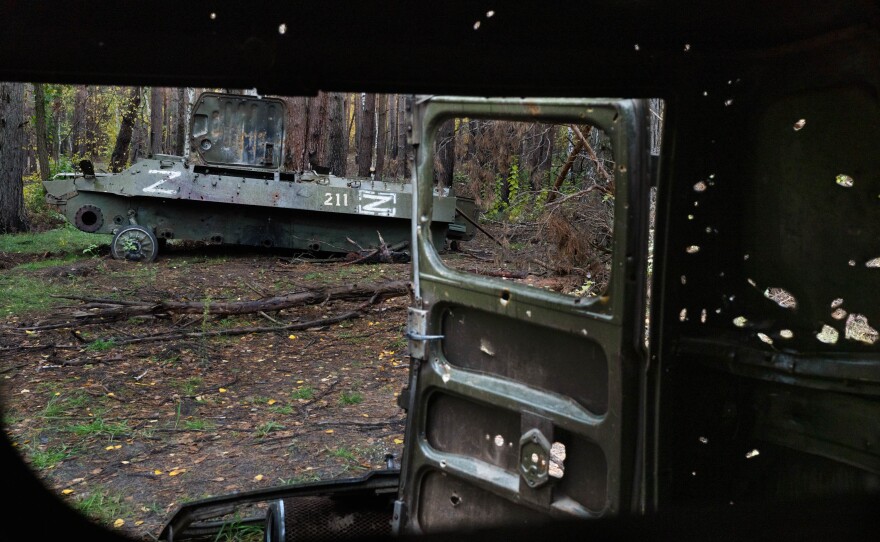 Abandonded vehicles with Russian markings are filled with holes in the woods in Izium in October.