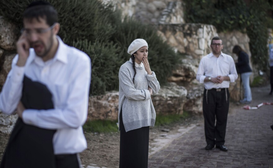 People react as they stand outside a synagogue on Tuesday in Jerusalem, Israel. Four Israelis were killed and several others wounded in a terror attack at the synagogue.