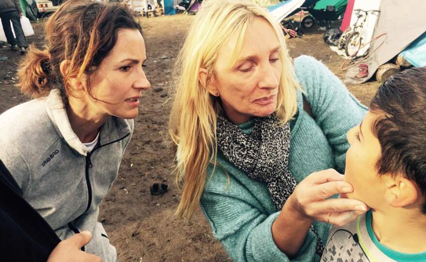 Teachers Virginie Tiberghien (left) and Nathalie Janssens check an Iraqi boy's mouth because he has a toothache. The camp has volunteer doctors to provide treatment.