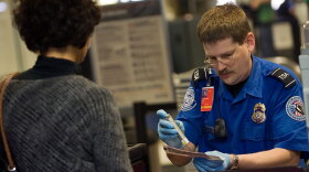 A TSA officer screens an airline passenger in Terminal C at Dallas/Fort Worth International Airport on Sunday.