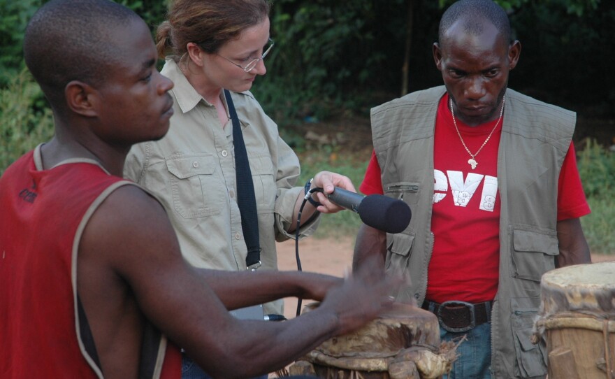 Anthropologist Nathalie Fernando of the University of Montreal records a Pygmy drummer while her interpreter looks on.