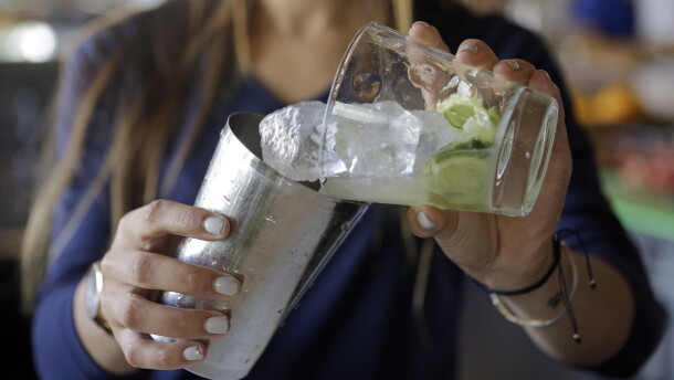 Bartender Rafaella Demelo adds sugar, 1.5 ounces of Leblon, and half a lime over ice in a shaker while preparing a caipirinha, Brazil's trademark cocktail.