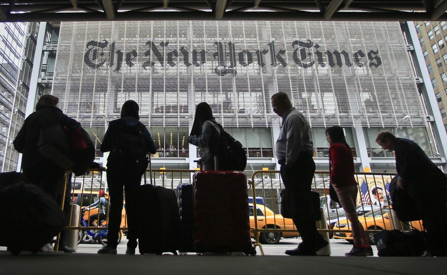Pedestrians wait for cabs across the street from The New York Times in 2014.