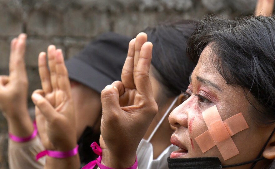 Protesters, wearing red makeup to simulate tears of blood, making the three-finger salute during a demonstration against the military coup in Hlaing Township, Yangon, Myanmar, on Thursday in a photo taken from a screenshot from AFPTV video.