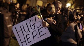 Tex Allen, facing camera, offers hugs for mourners during a vigil in memory of victims of a warehouse fire in Oakland, Dec. 5, 2016.