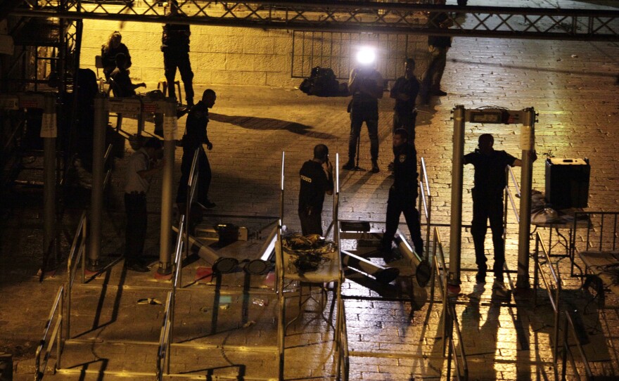 Workers dismantle metal detectors early Tuesday outside Al-Aqsa Mosque compound in Jerusalem's Old City.