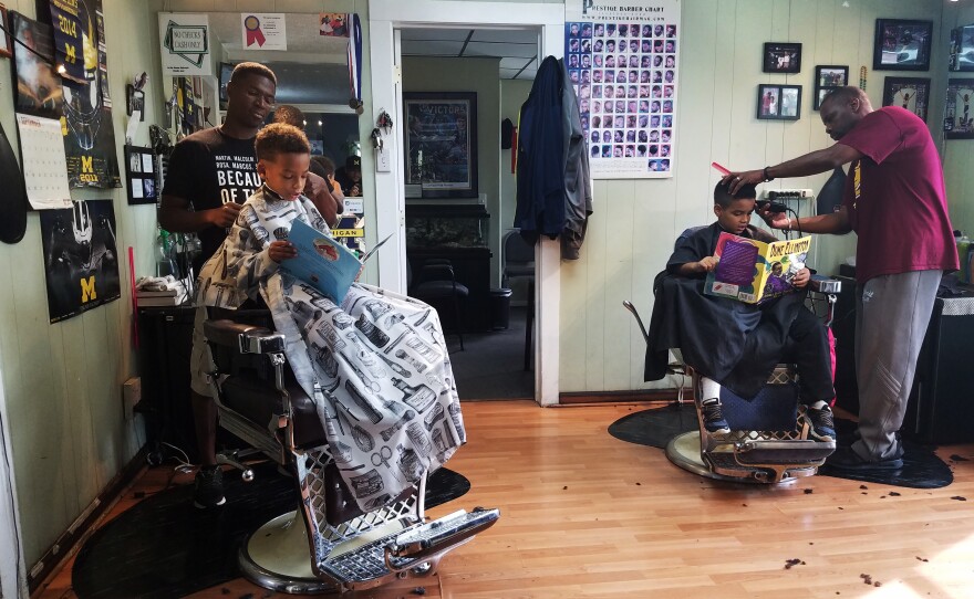 Joziah and Jozef read to their barbers at the Fuller Cut in Ypsilanti, Mich. As part of the barbershop's literacy program, children get $2 off their cut for reading a book to their barber.