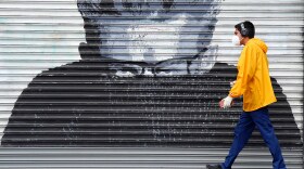 A pedestrian in a mask during the coronavirus outbreak walks by a mural of the late actor James Dean on Hollywood Boulevard, Saturday, April 4, 2020