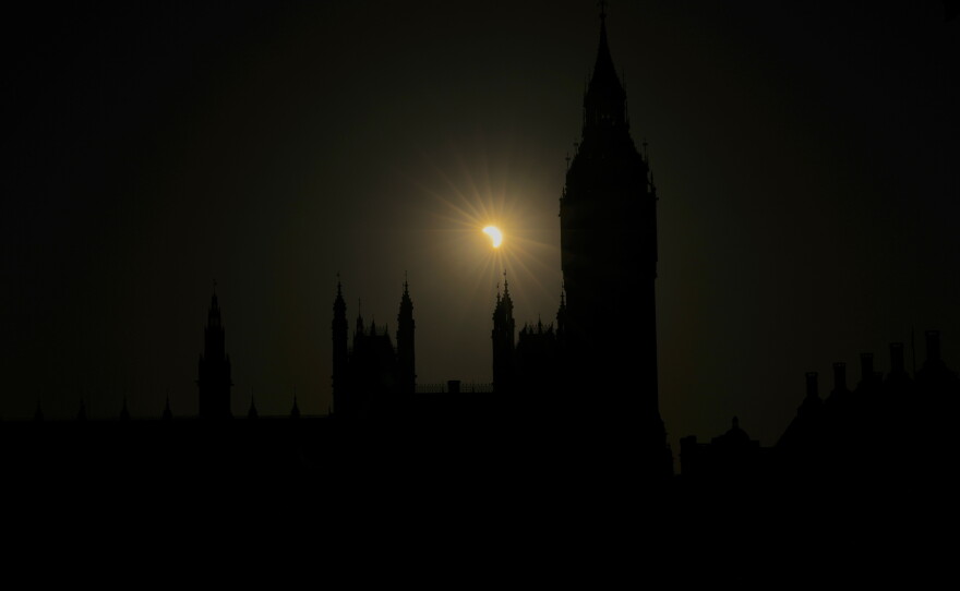 A partial solar eclipse is seen above the Houses of Parliament in London, Wednesday, Aug. 12, 2026.