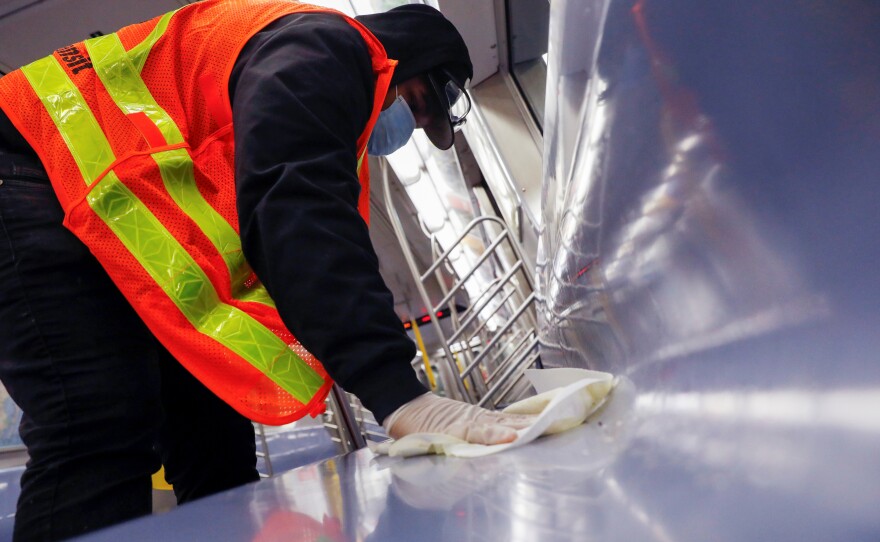 A worker wipes down surfaces on a New York City subway car to disinfect seats during the coronavirus outbreak. The CDC is clarifying its guidance on touching surfaces after a change to its website triggered news reports.