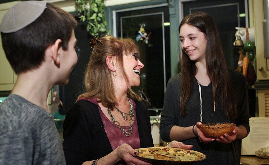 Ruth Seif (center) teaches her grandchildren Anna (right) and Aaron Rabinowitz (left) how to make traditional potato latkes (pancakes).