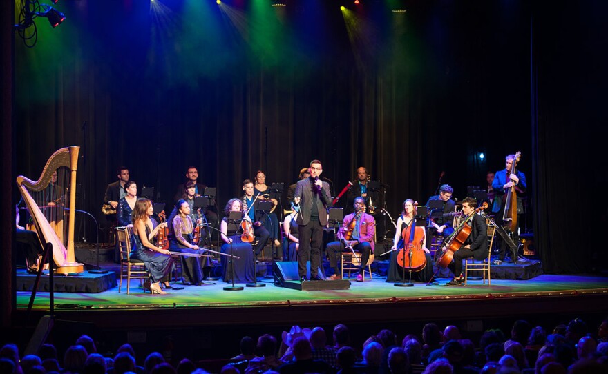 Maestro Luke Frazier (center with microphone) speaks to the audience with American Pops Orchestra and Ohio University singers.