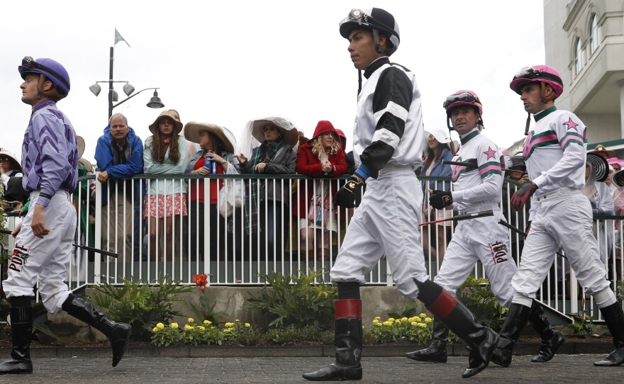 Jockeys walk through the paddock in a race before the 143rd running of the Kentucky Derby horse race at Churchill Downs Saturday.