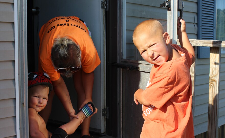 Katie Lester helps her two sons, Memphis (left) and Mason, put on shoes at their home in Belfast, Tenn. TennCare mailed the Lesters' Medicaid termination letter to a horse pasture, which is why the family did not realize their uninsured status.