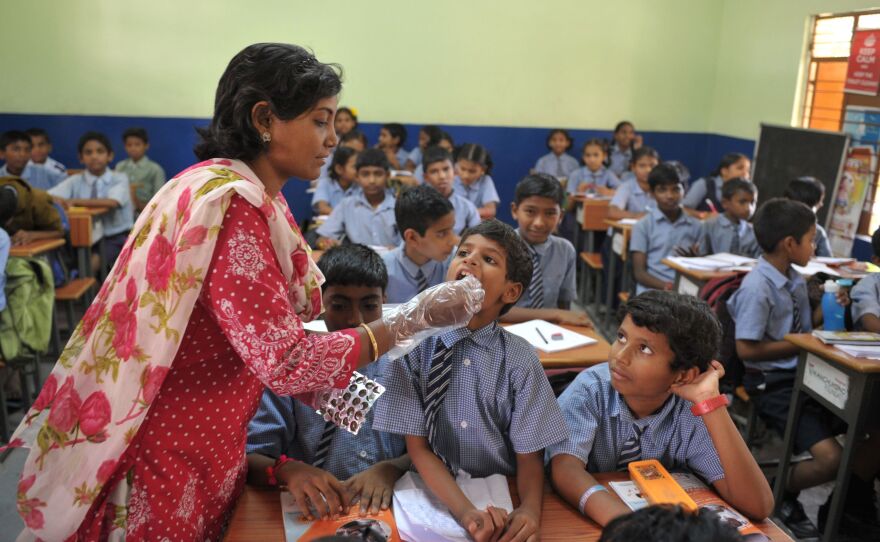 A teacher gives a deworming tablet to a student during National Deworming Day at a high school in Hyderabad, India in 2017.