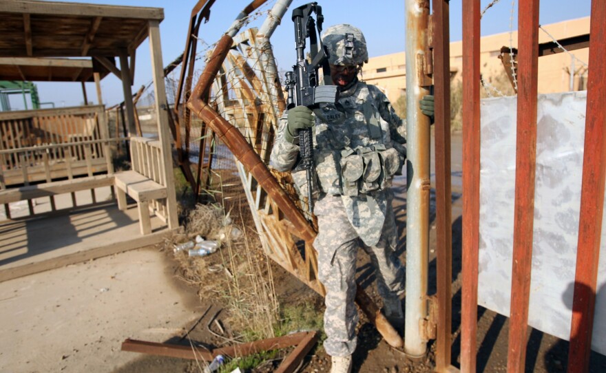 A U.S. soldier walks through a fence on Monday at the Taji base complex north of the capital Baghdad.