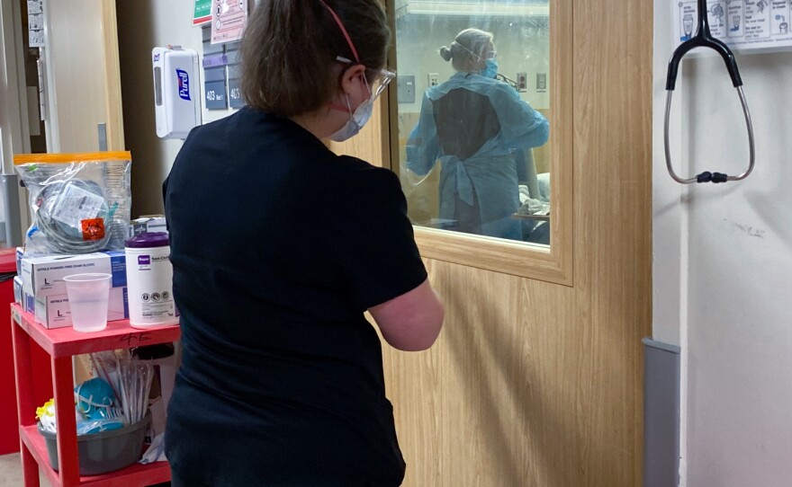 A health care worker peers into a patient's room while a medical team attends to a patient in the COVID-19 ward at Harborview Medical Center in Seattle on January 14, 2022.