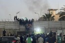 Protesters scale a wall at the Swedish Embassy in Baghdad Thursday. Protesters angered by the planned burning of a copy of the Quran stormed the Embassy early Thursday, breaking into the compound and lighting a small fire.