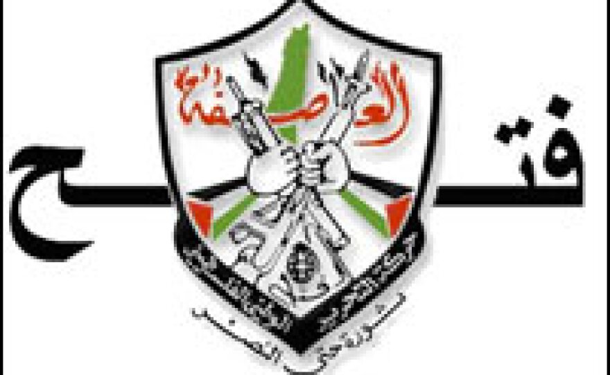 The official Fatah emblem depicts two fists holding rifles, with a hand grenade in between. In the background is a map of Israel and the occuppied territories.